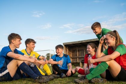 Groupe de jeunes footballeurs souriant lors d'une pause hydratation pendant un stage de foot estival